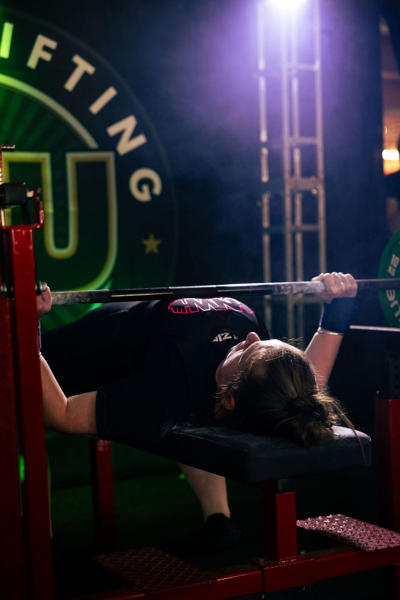 Bench press attempt seen from the head of the bench, bar locked out under the stage truss