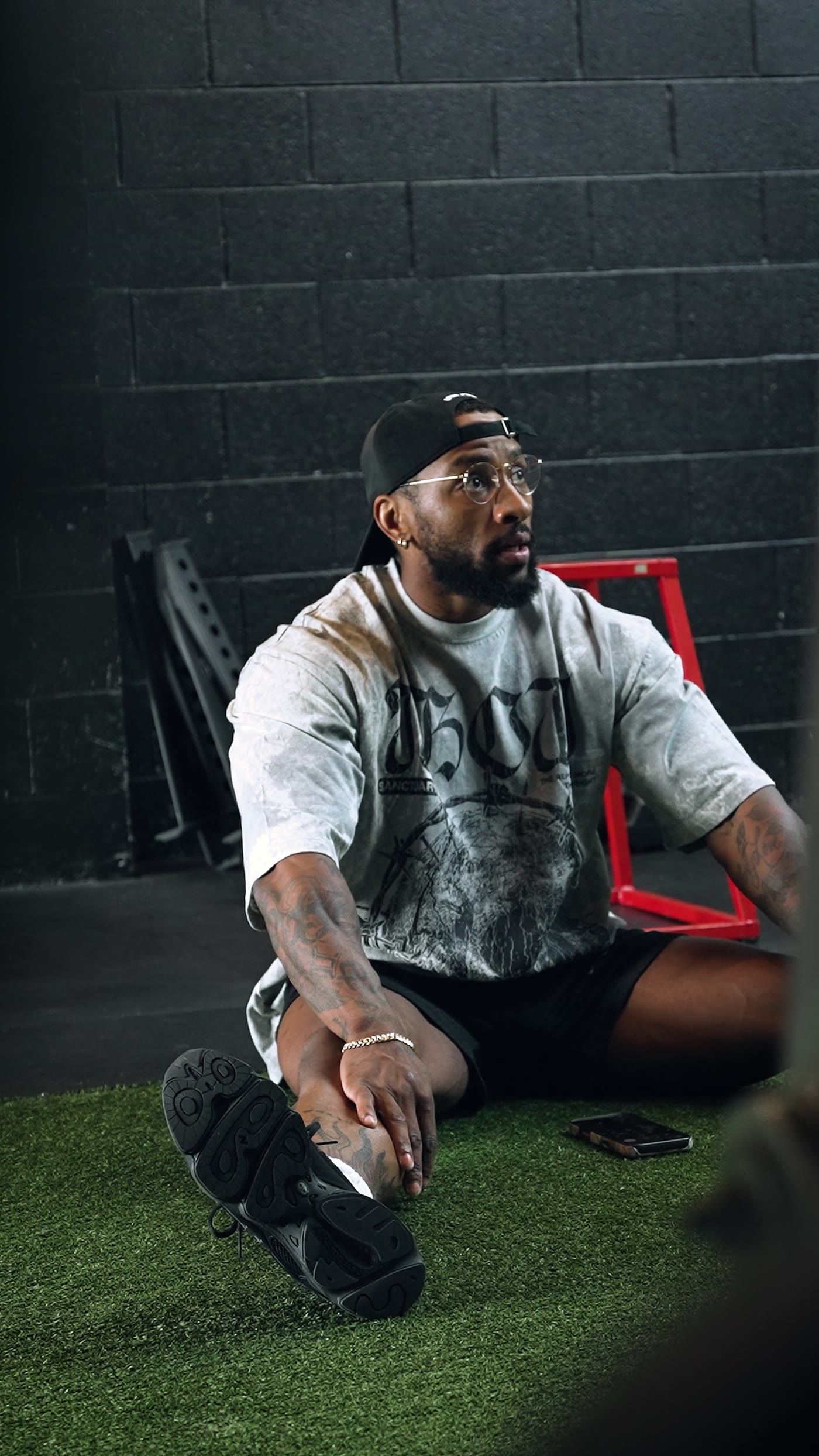 RIKFLEX stretching on the turf in a backwards cap and glasses, frame from the film