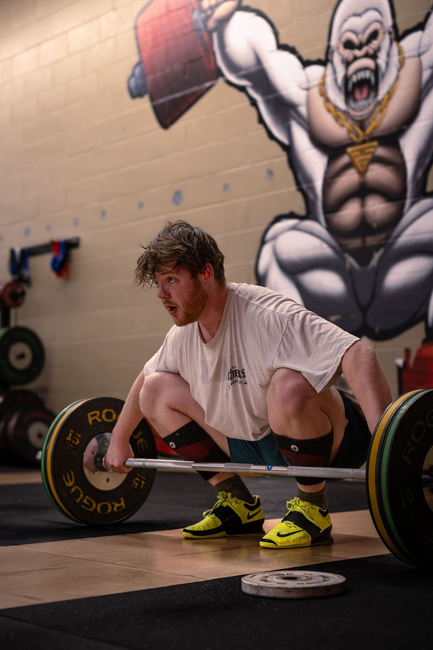 Member setting up a deadlift in front of the gorilla mural at Training Grounds