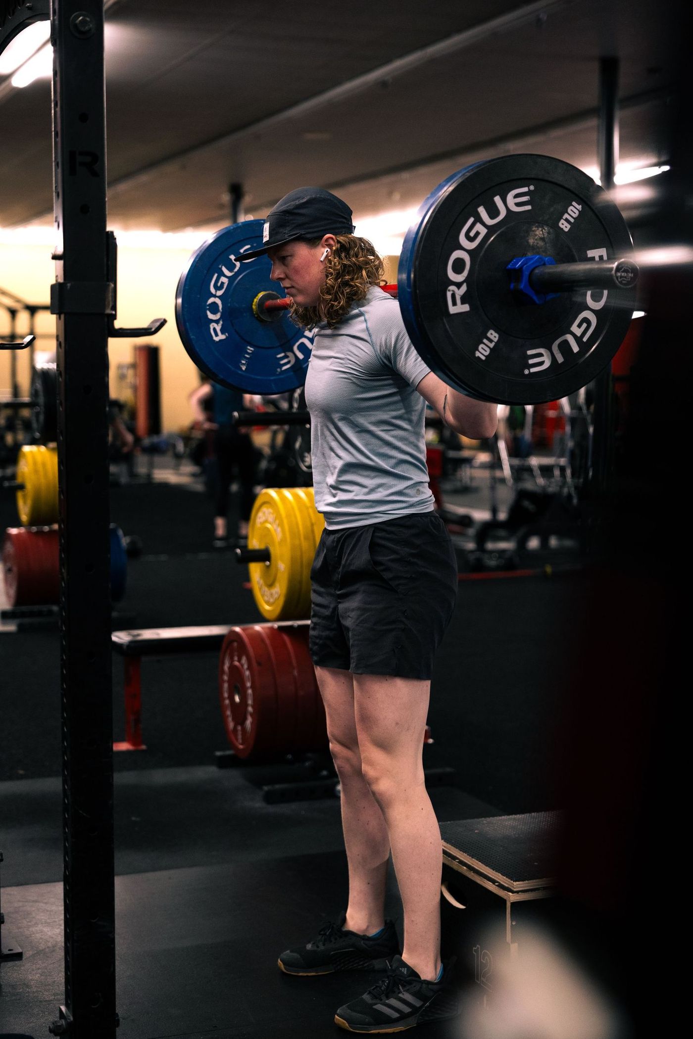 Member under a loaded bar in the squat rack at Training Grounds