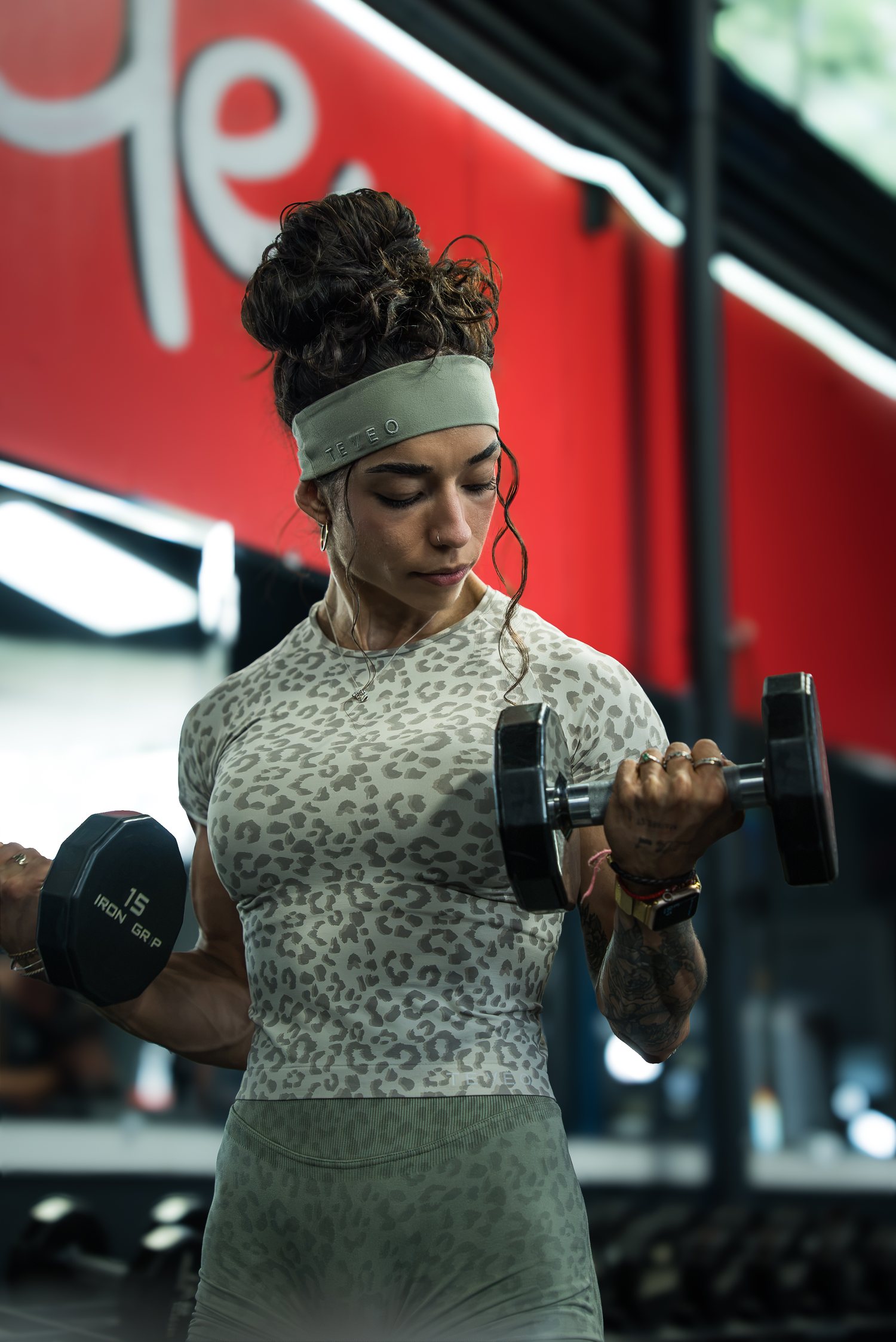 Roxy Cisneros curling a dumbbell in a leopard print tee