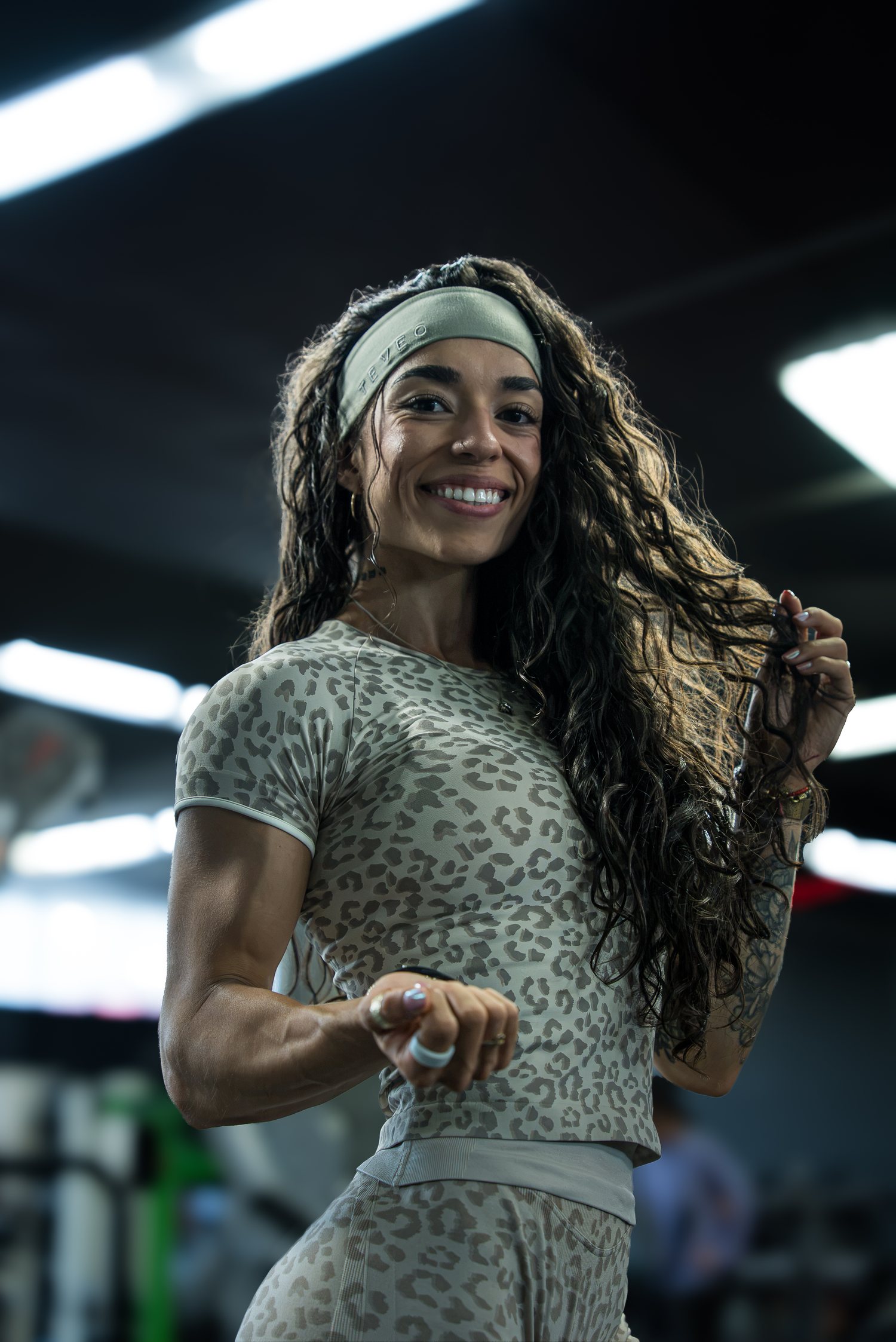 Roxy Cisneros smiling with her hair down, one hand in her curls