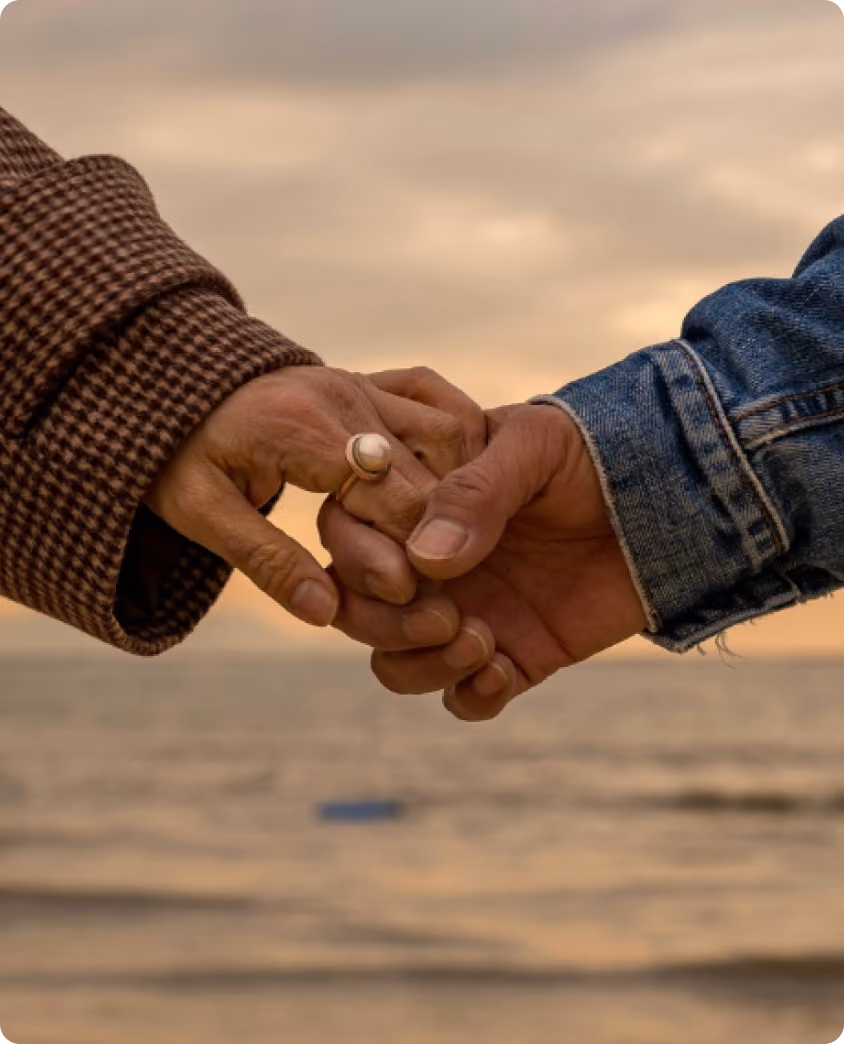 Two people holding hands at sunset