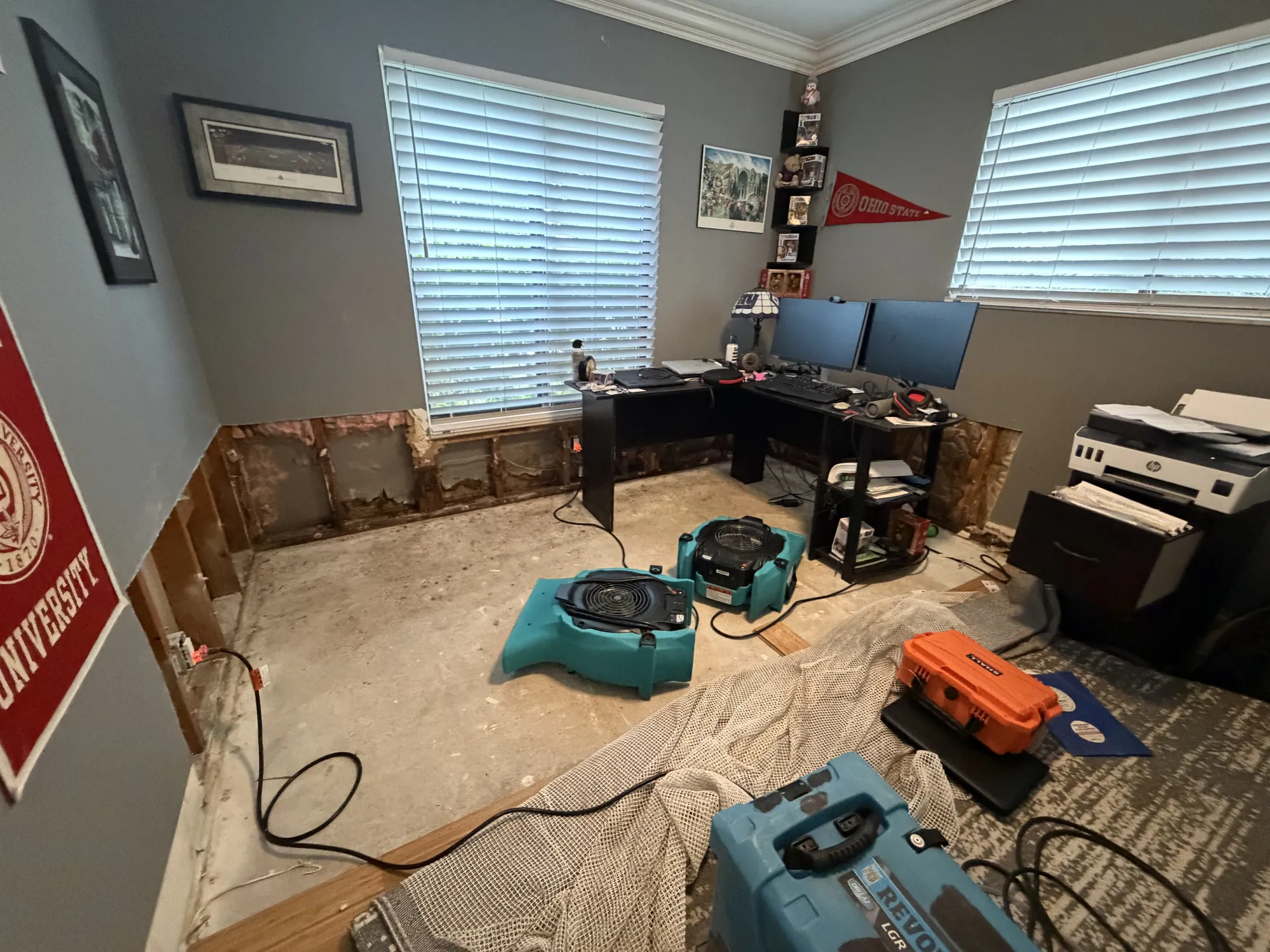 Air movers drying a home office subfloor after water-damaged drywall was removed in South Florida