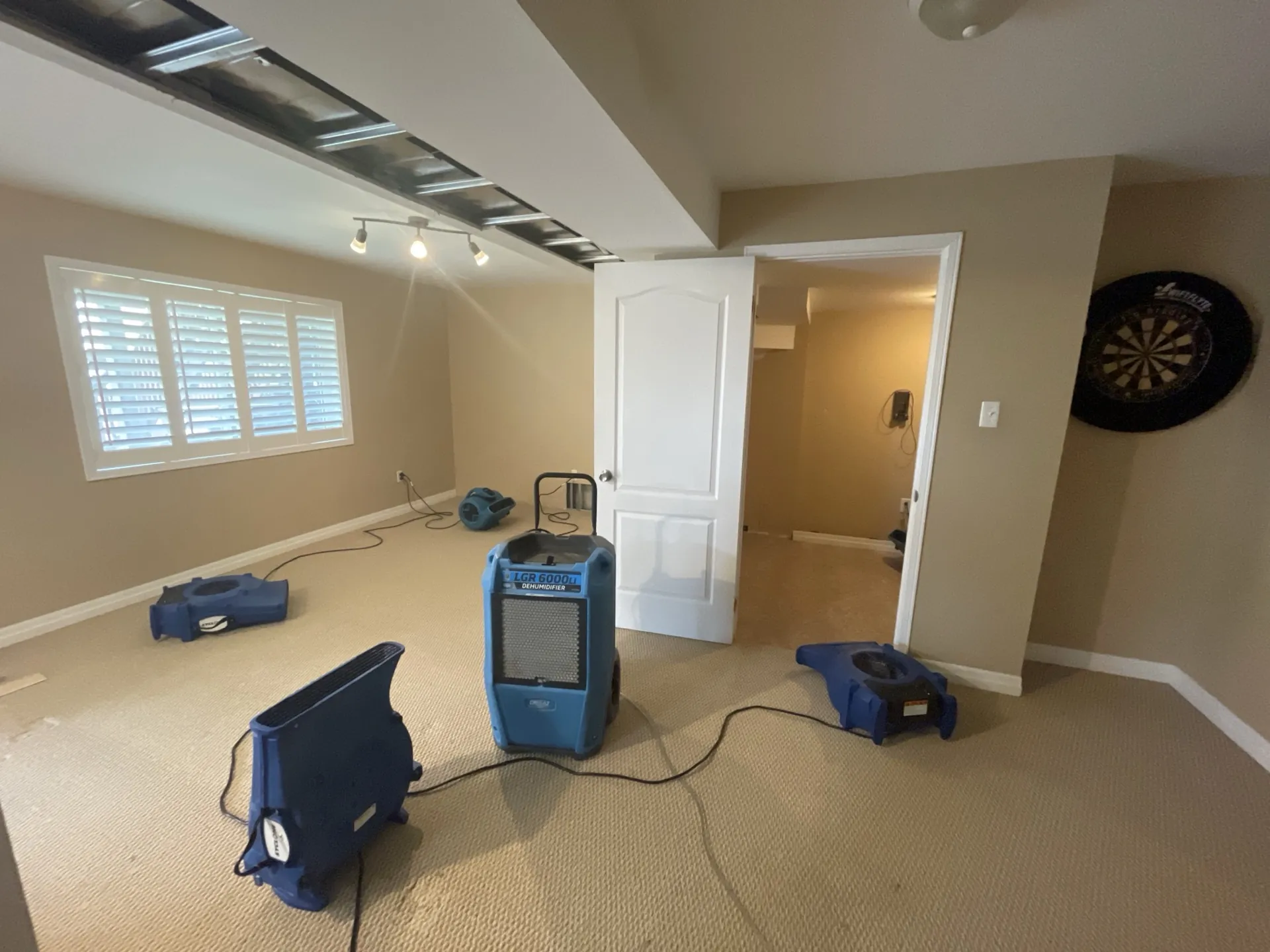 Dehumidifier and four air movers drying carpet in a family room in South Florida