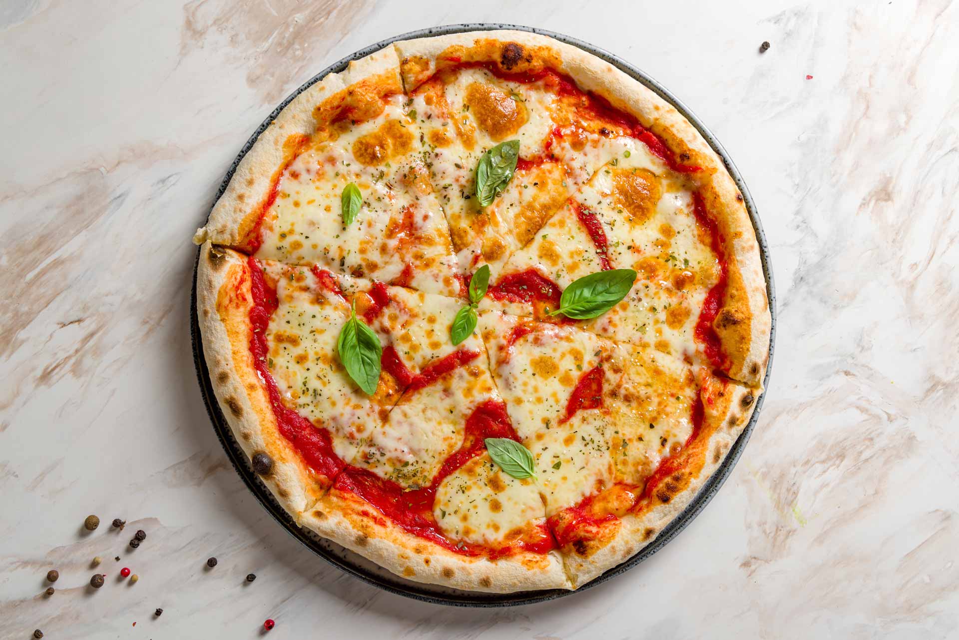 Margherita pizza with melted cheese, tomato sauce, and fresh basil leaves on a plate.