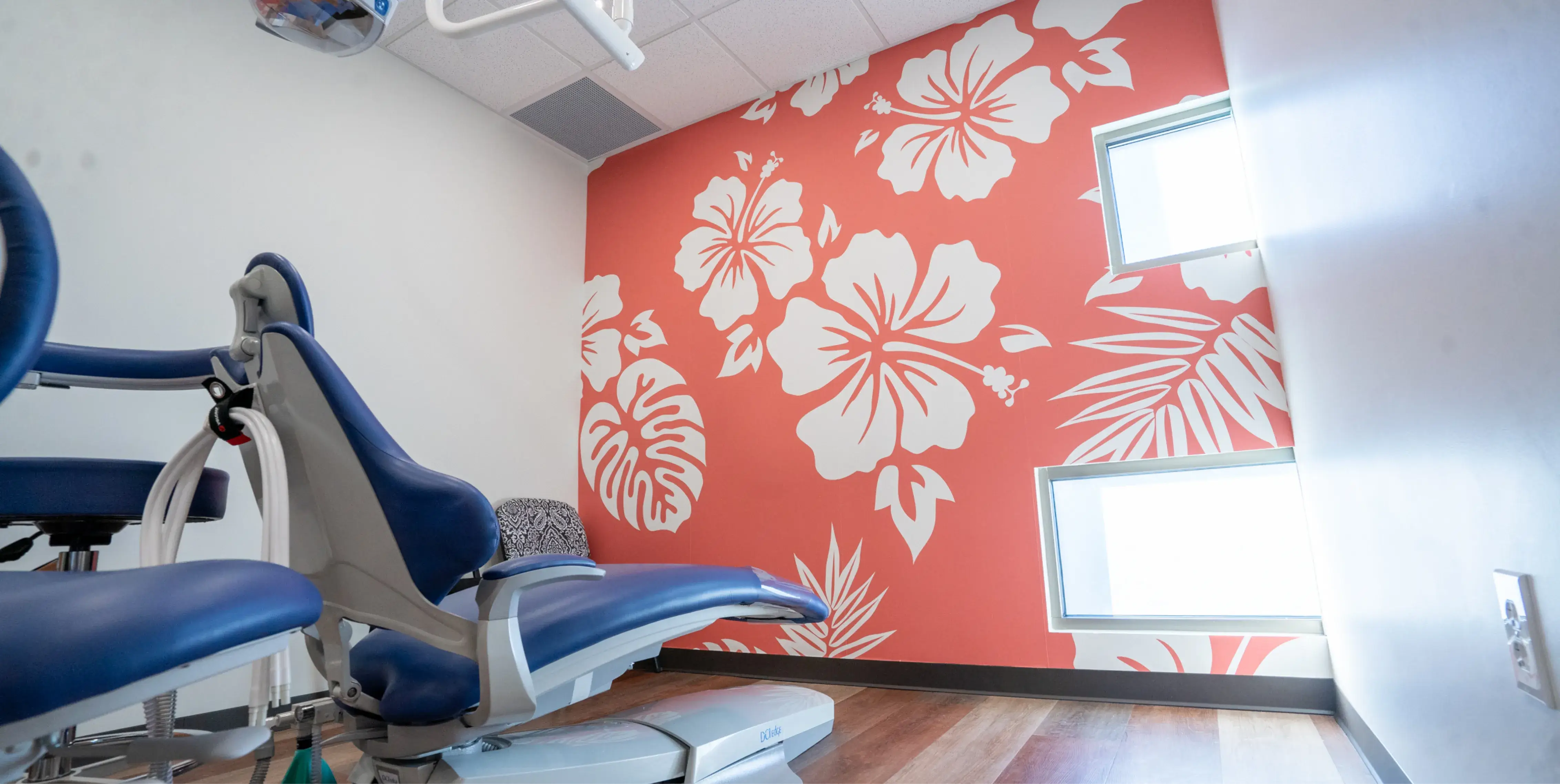 A dentist's chair in front of a floral wallpaper.