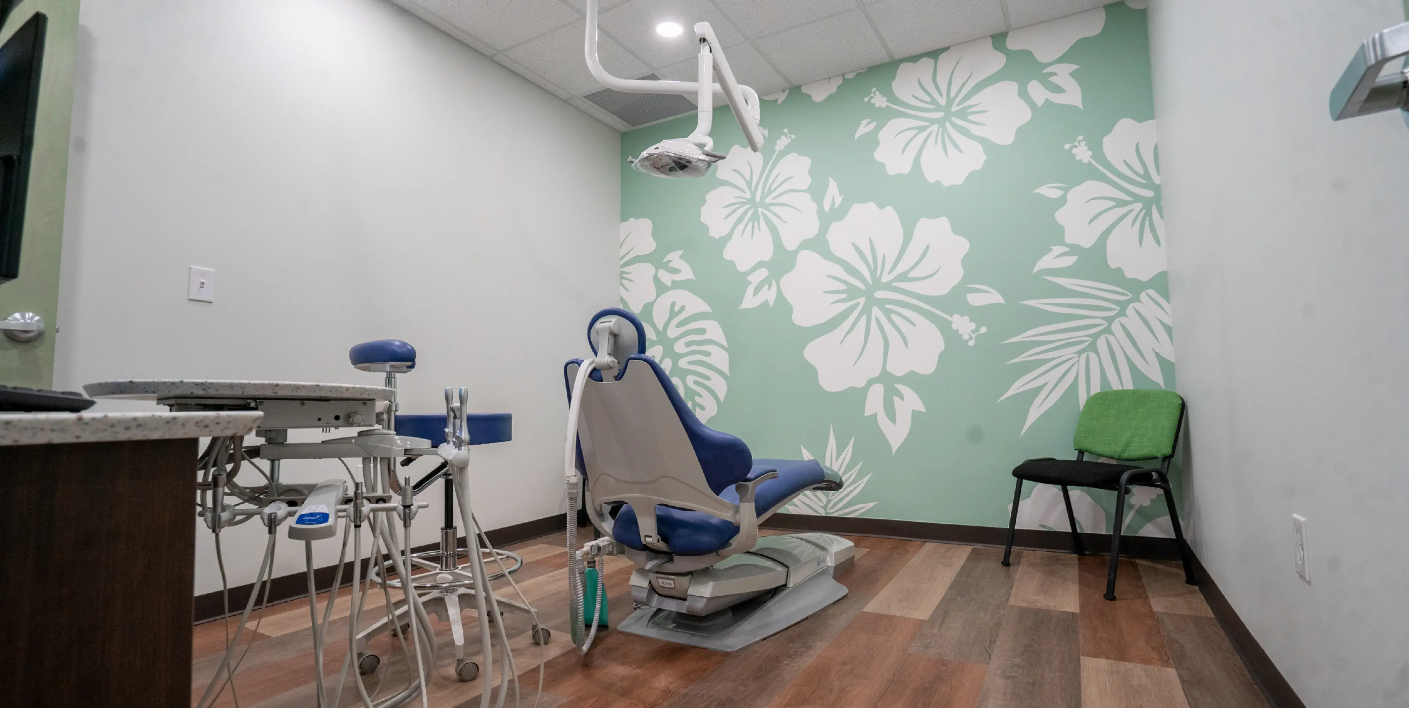 A dentist's office with a chair, stools, and a sink.