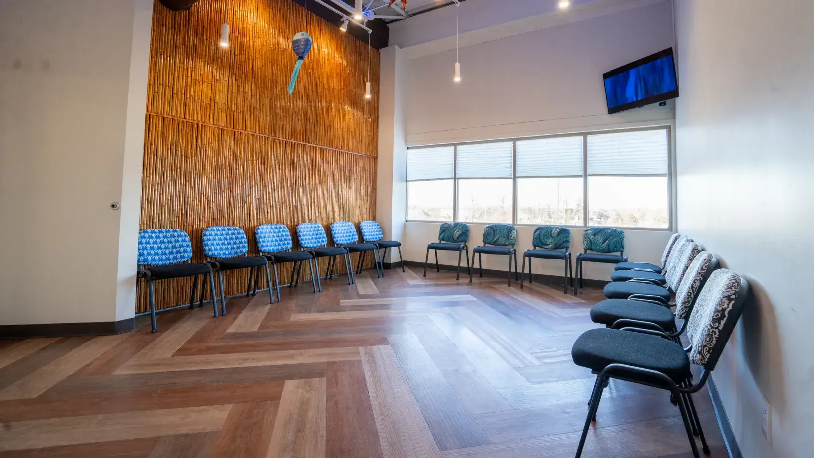 A row of chairs in a room with a tv on the wall.