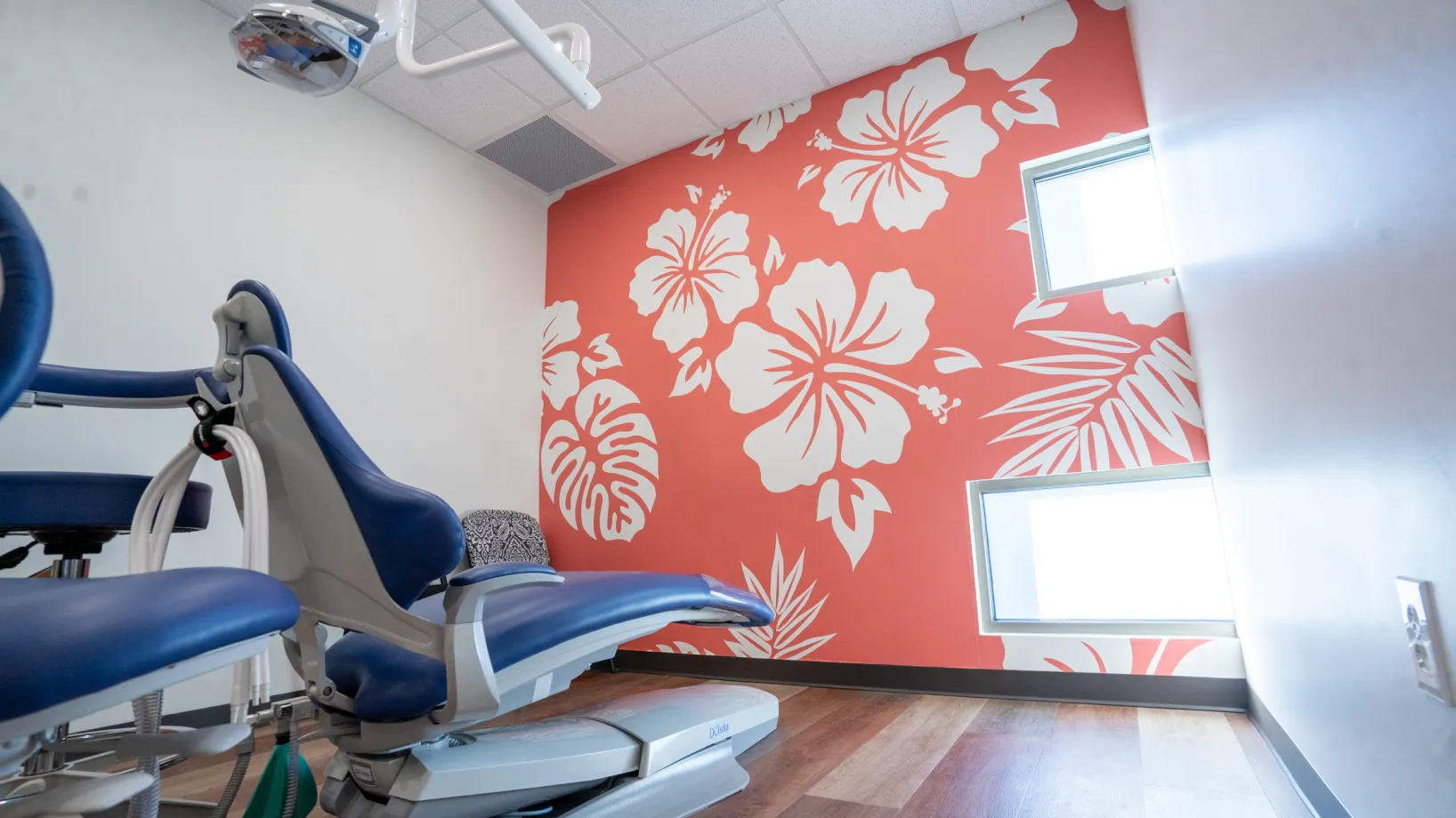 A dentist's chair in front of a floral wallpaper.