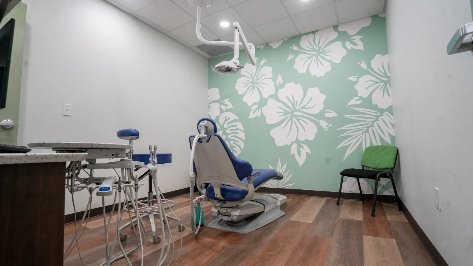 A dentist's chair in front of a floral wallpaper.