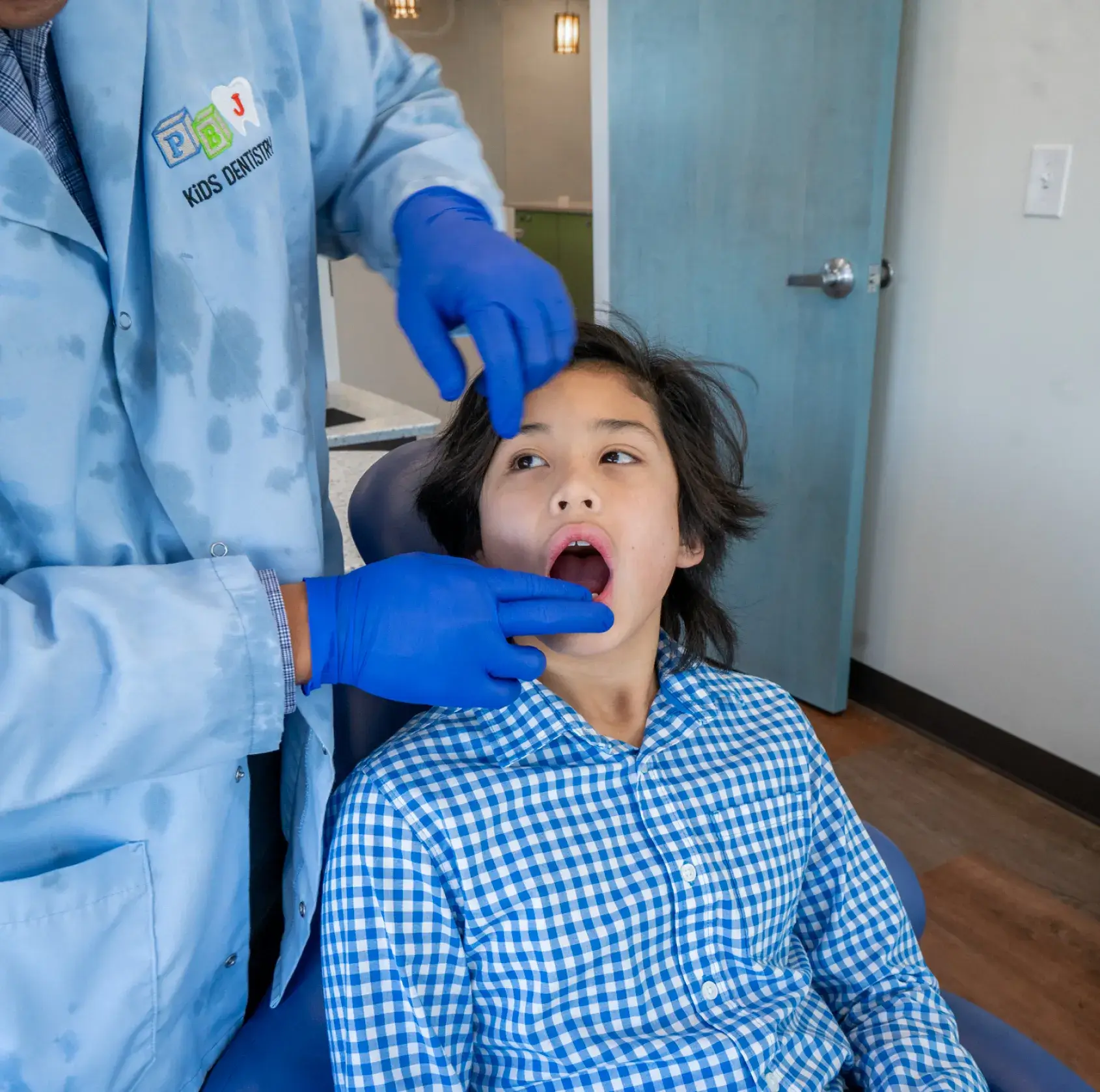A young boy getting his teeth checked by a doctor.