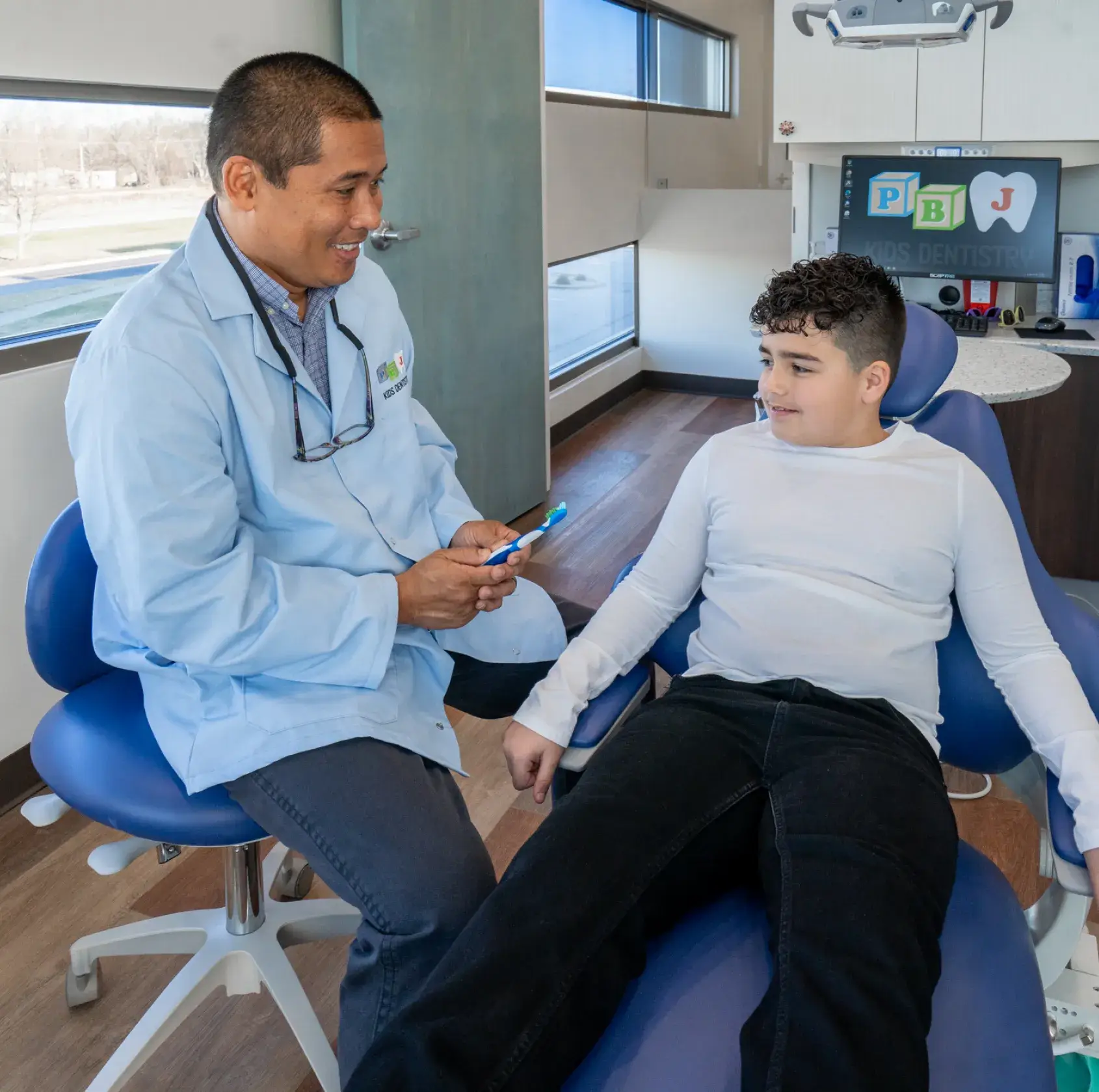 A young boy sitting in a chair with a doctor.