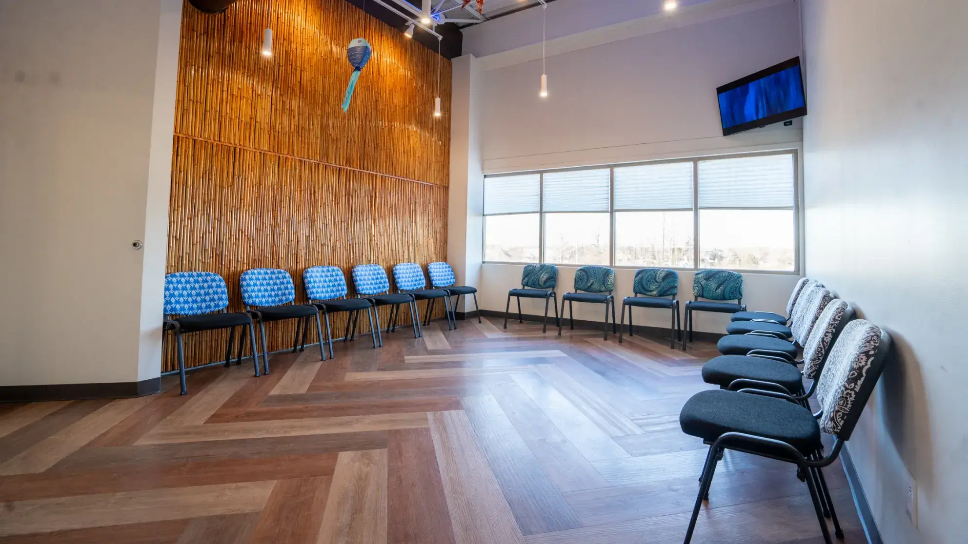 A row of chairs in a room with a tv on the wall.