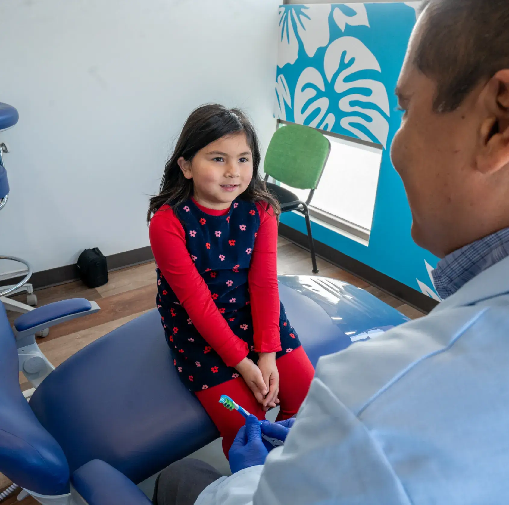 A little girl sitting in a dentist chair.