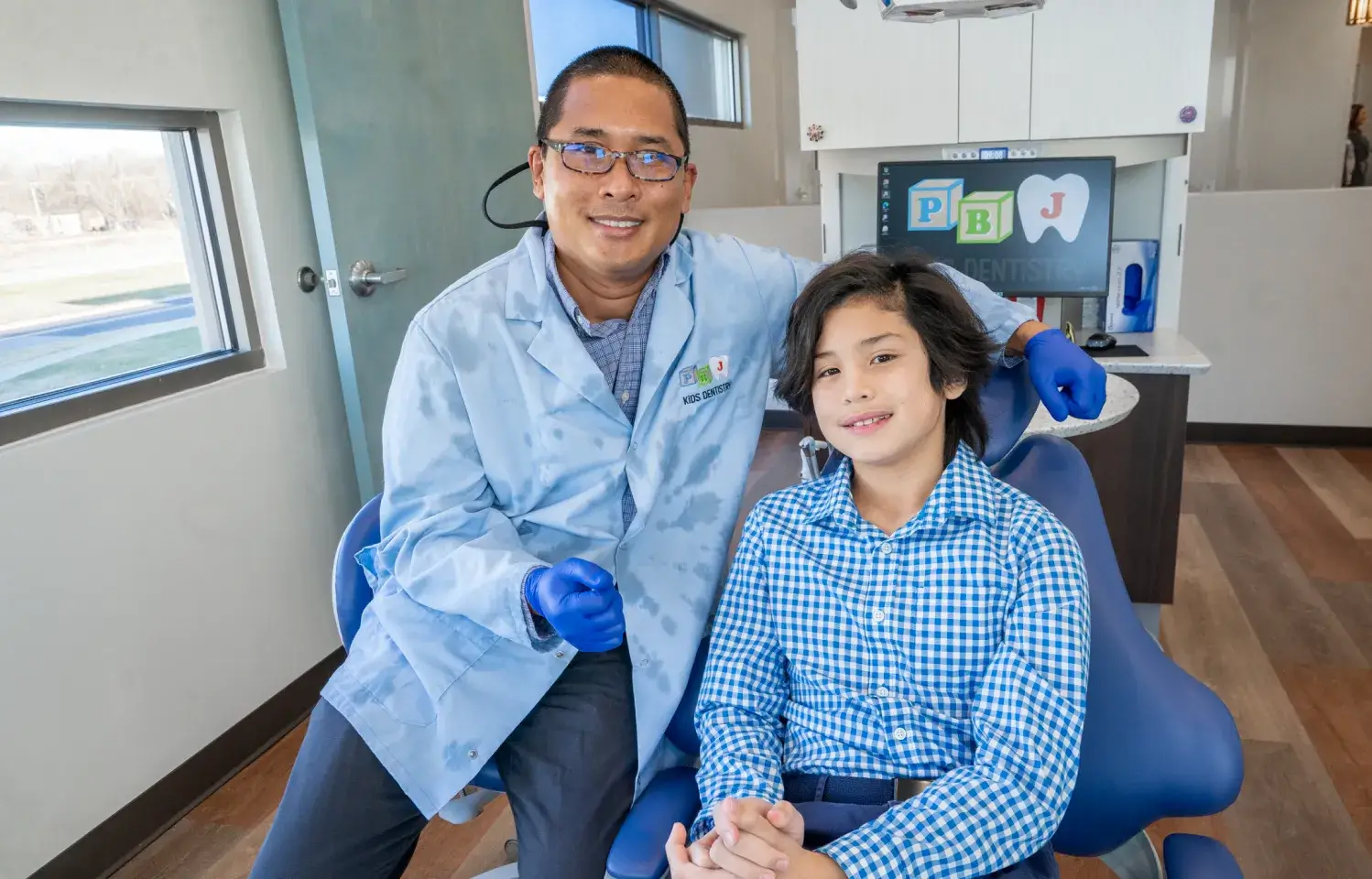 A man sitting next to a little boy in a dentist chair.