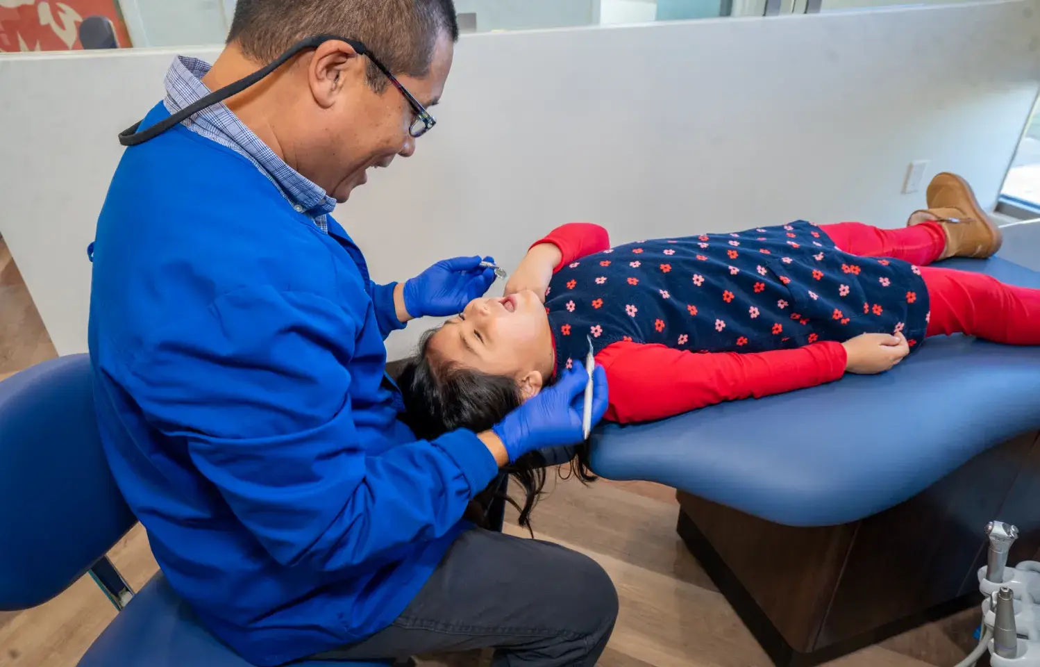 A little girl getting her teeth checked by a dentist.