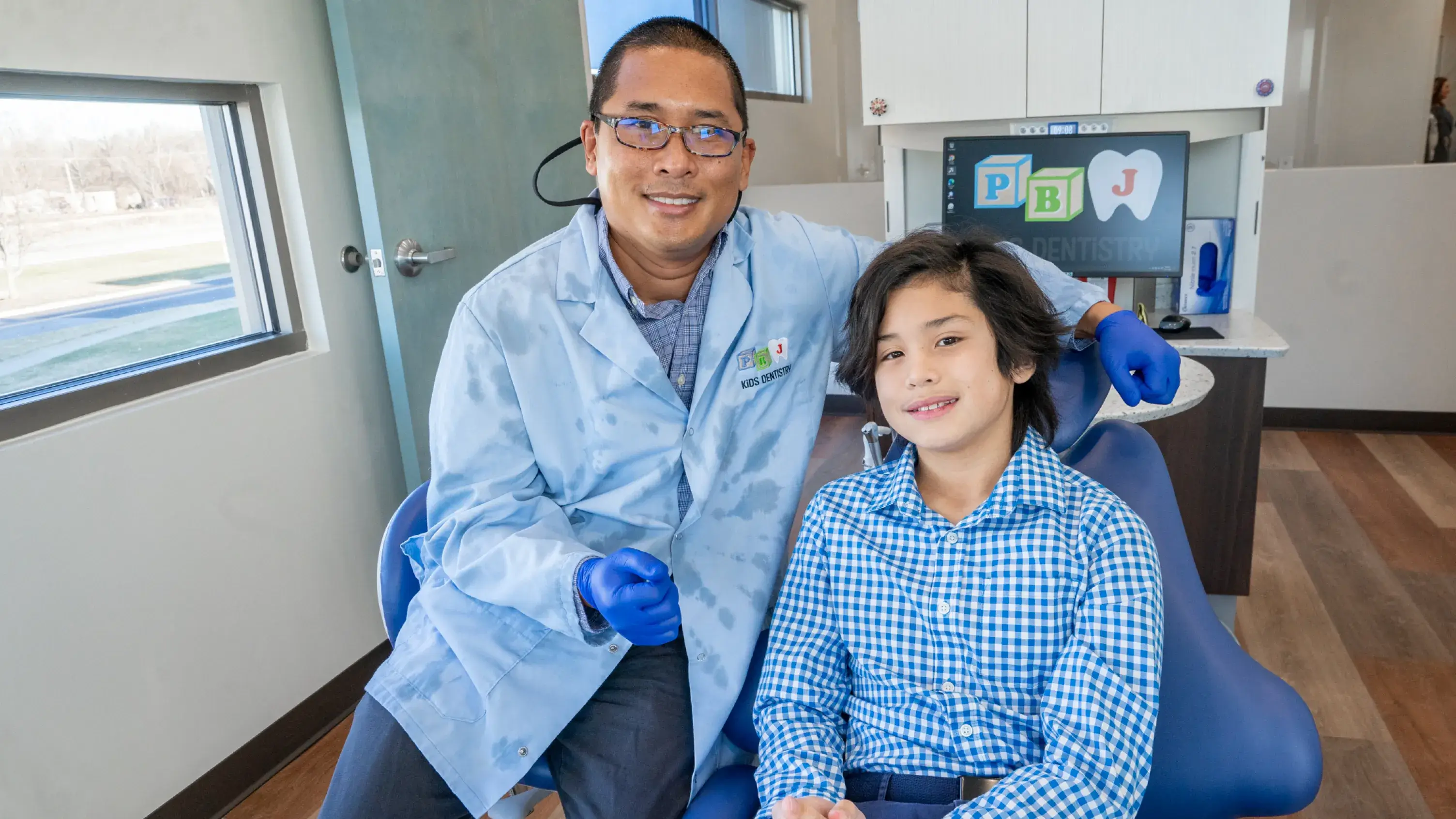 A man sitting next to a little girl in a dentist chair.