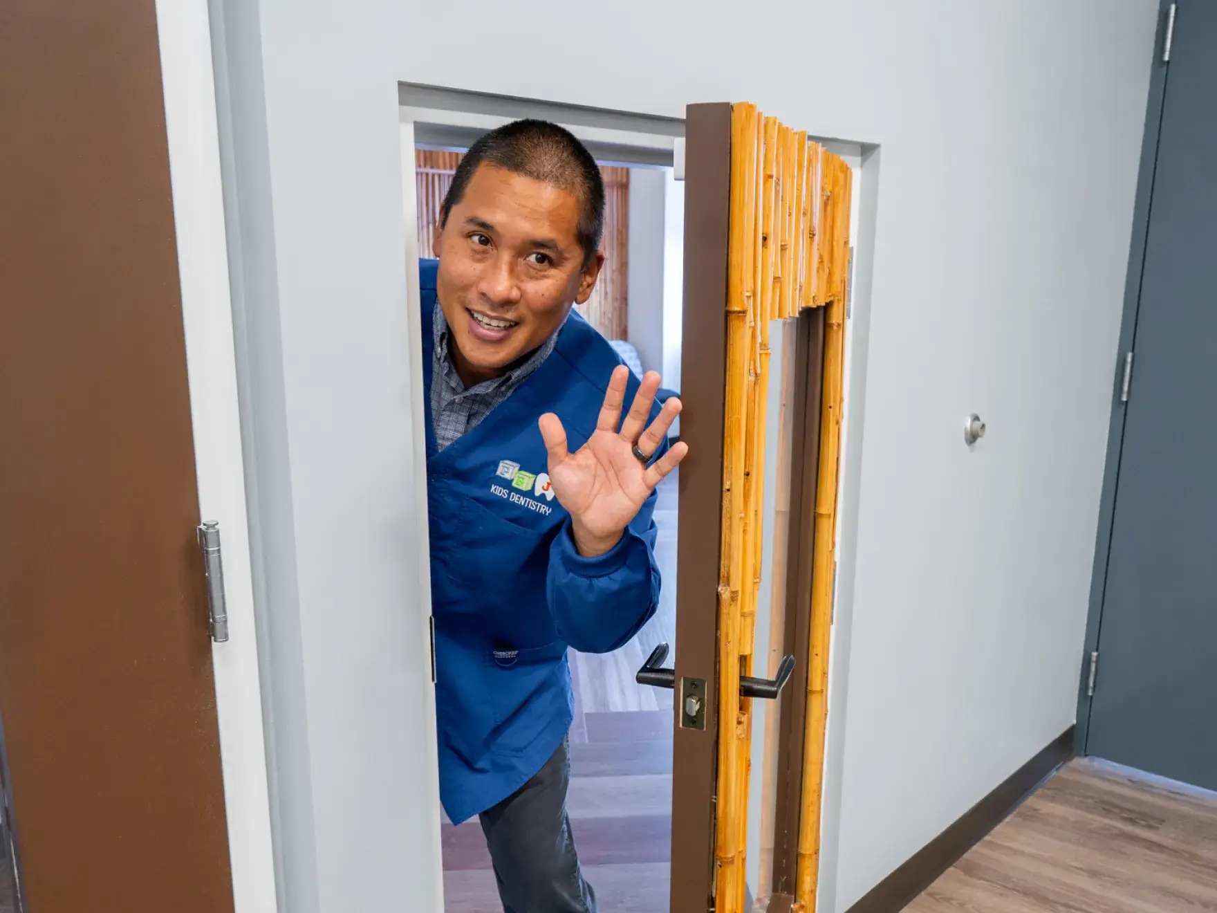 Dr. Philippe Bautista, DMD in a blue jacket is opening a door.