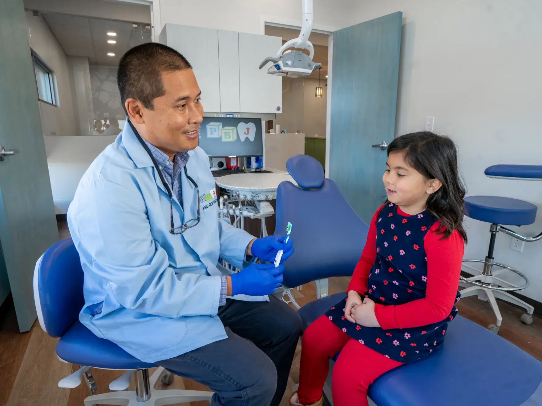 Dr. Philippe Bautista, DMD sitting in a dentist chair with a little girl.