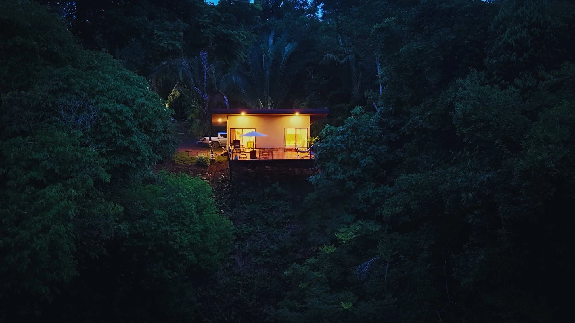 Toucan Lodge glowing at dusk, alone in the rainforest canopy