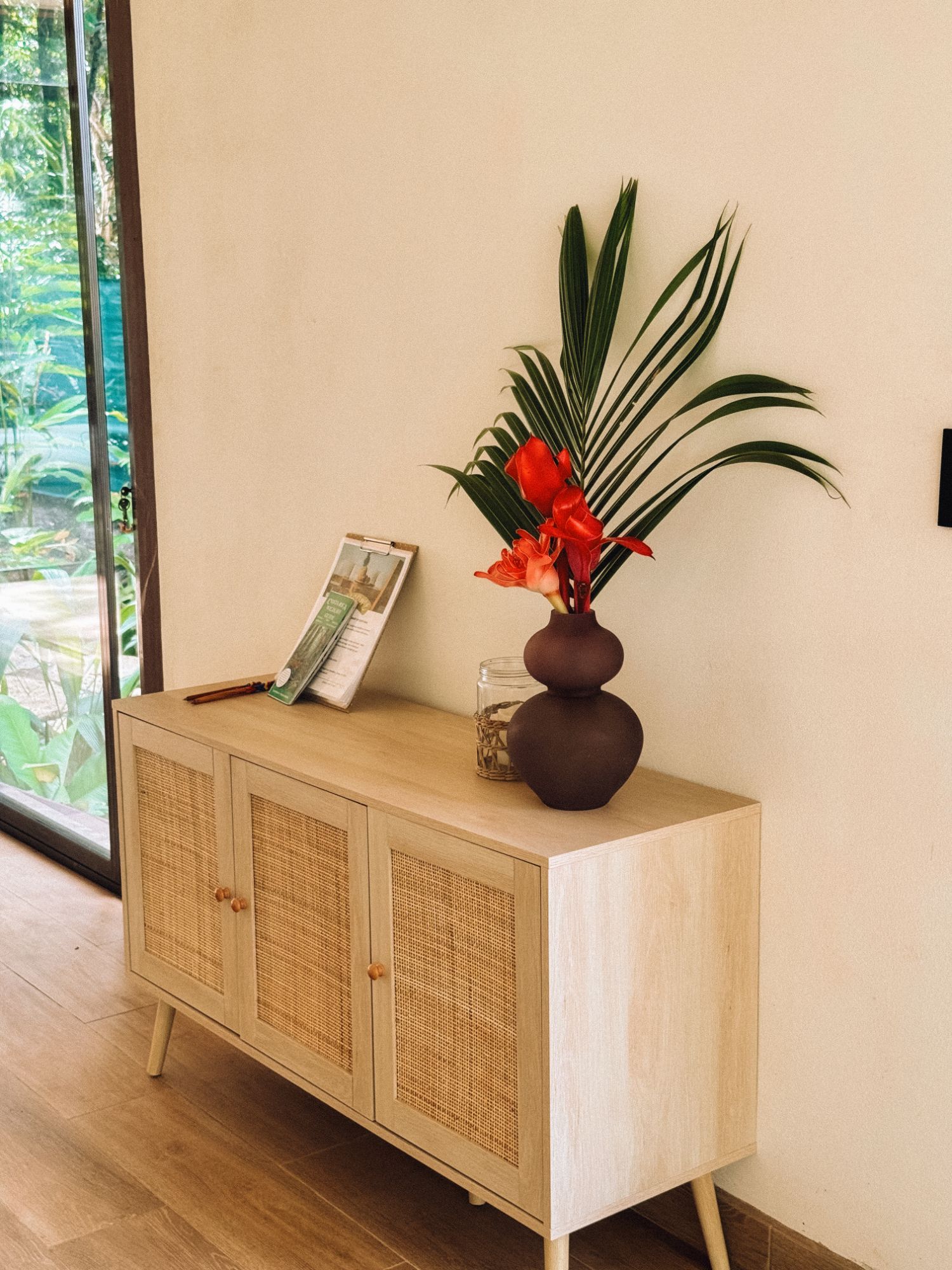 Rattan sideboard with red heliconia beside the garden door