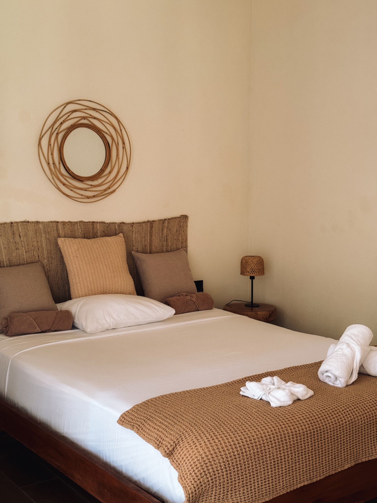 Bedroom with a woven headboard and a round rattan mirror