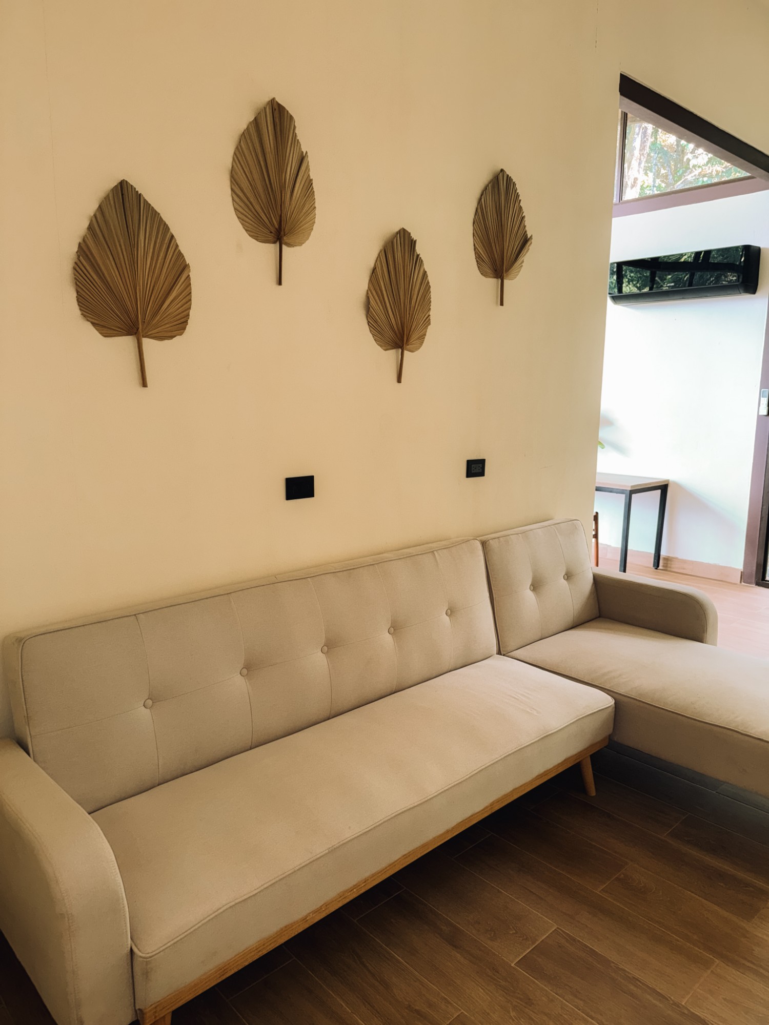Sofa below four dried palm leaves