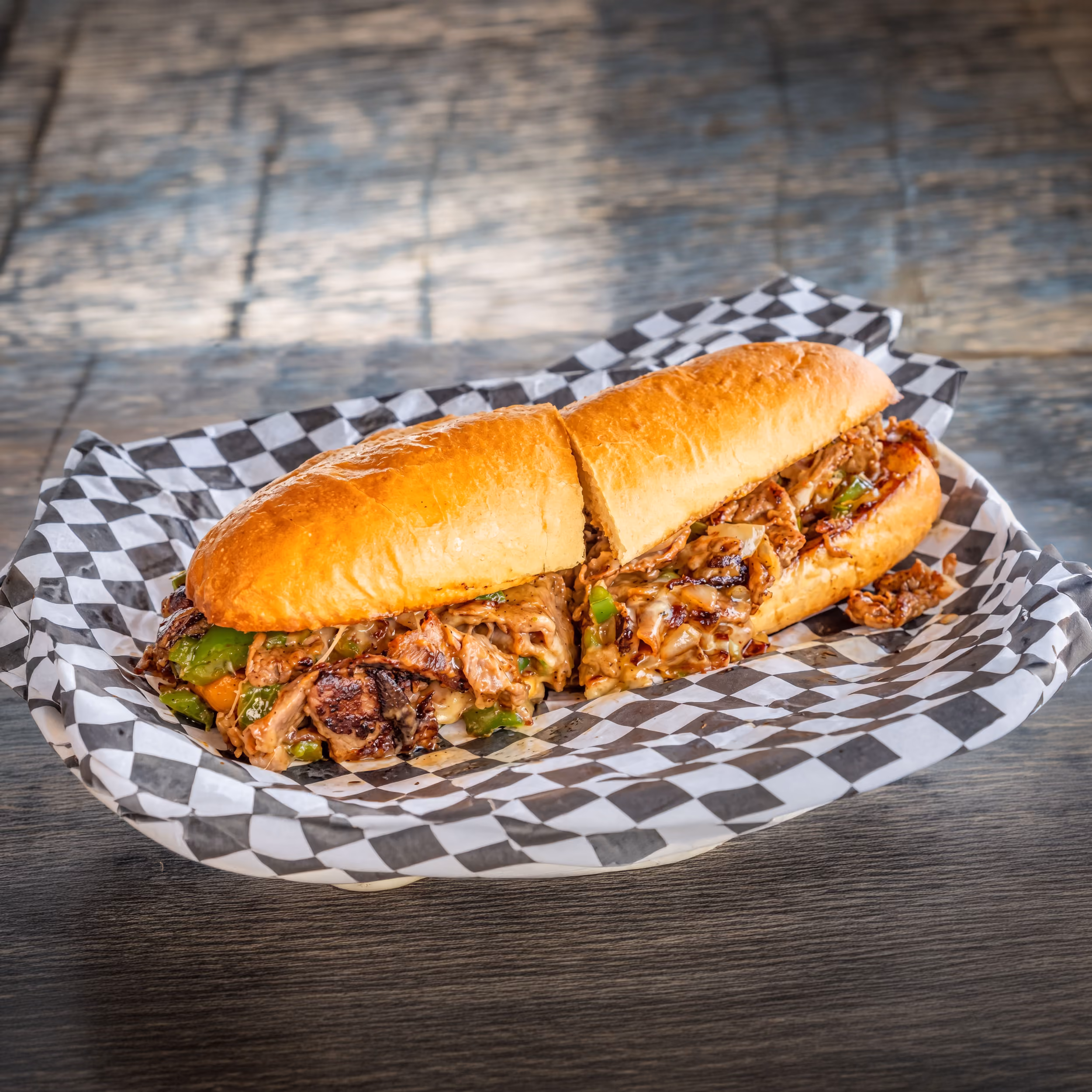 Cheesesteak sandwich on checkered paper.