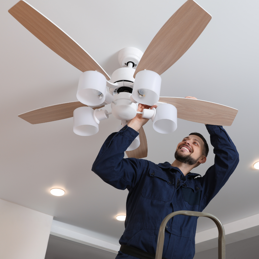 A technician replacing a ceiling fixture from a ladder