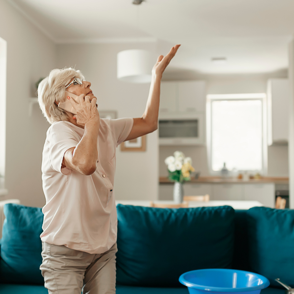An older woman on the phone under a ceiling leak