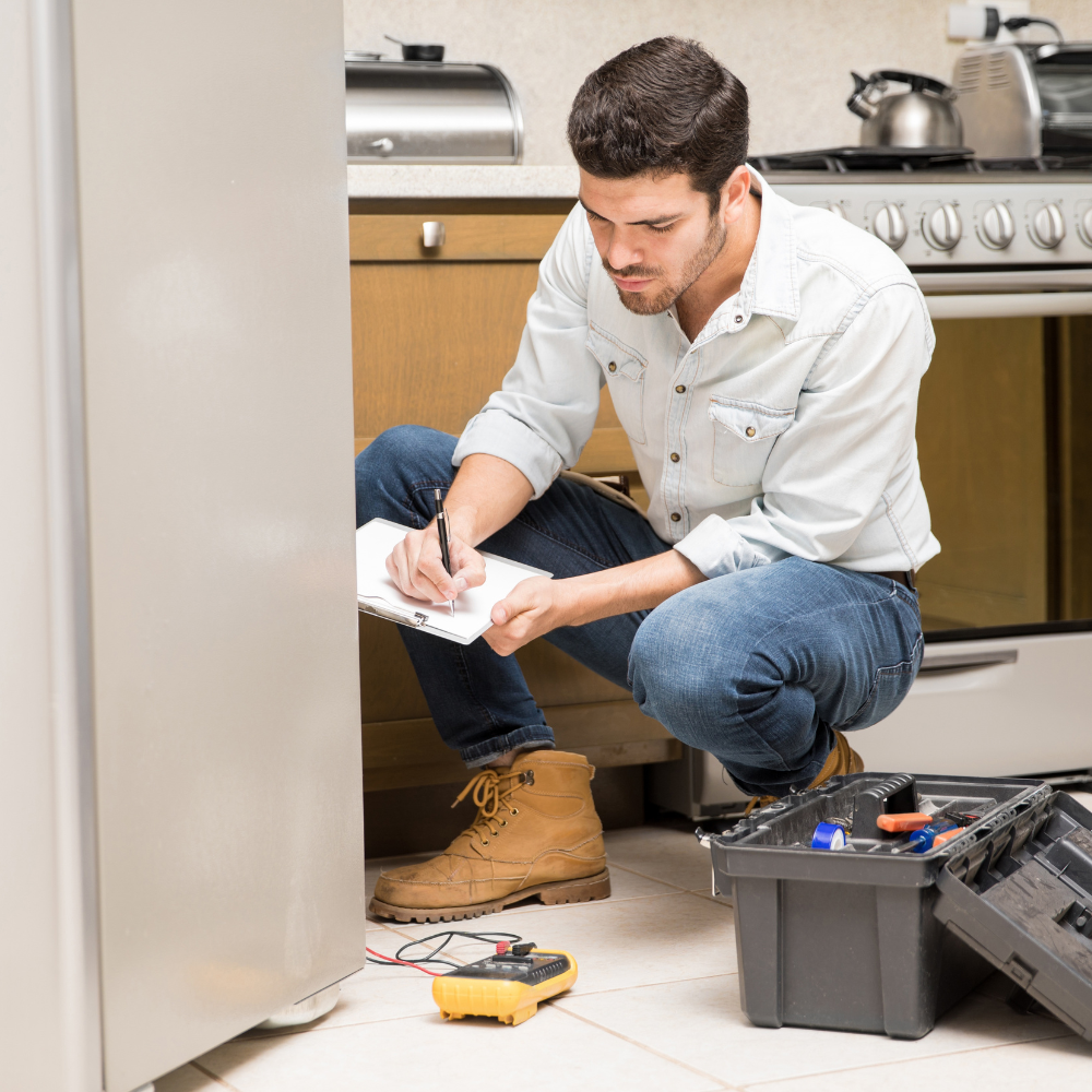 A technician inspecting an appliance and writing notes