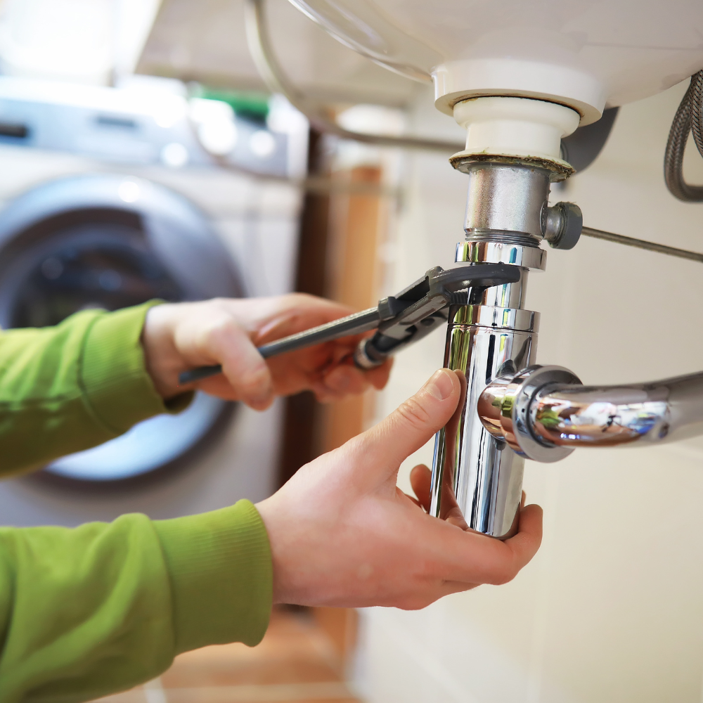 A plumber tightening a sink trap under a basin