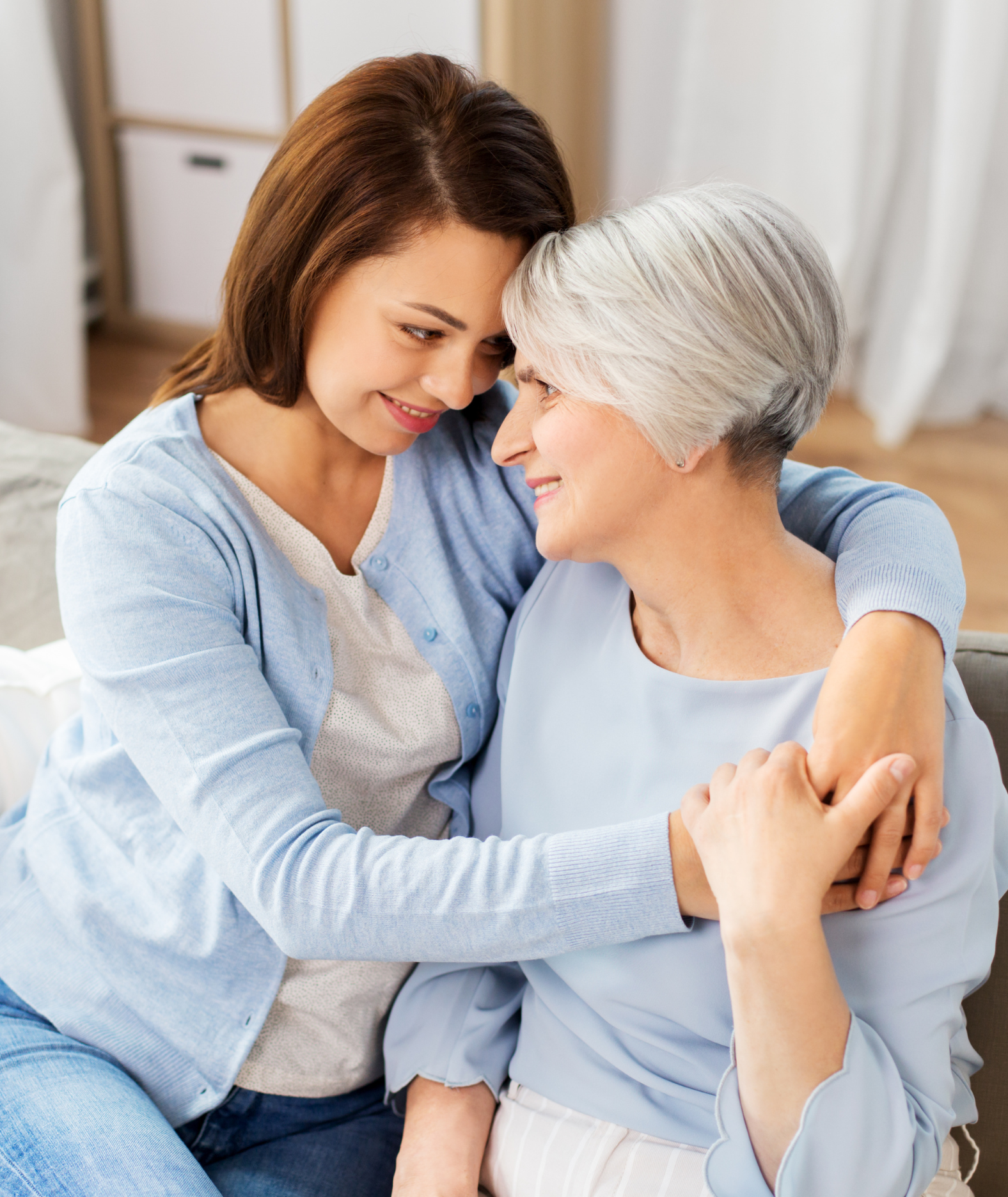 An adult daughter embracing her mother at home