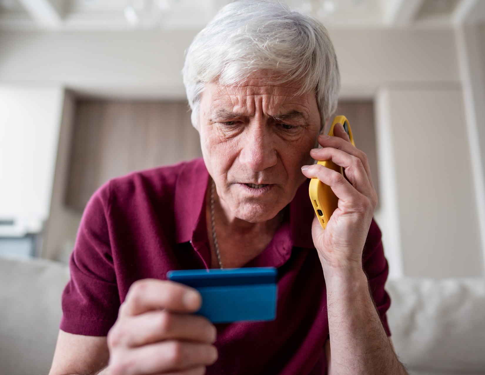 An older man on the phone holding a payment card