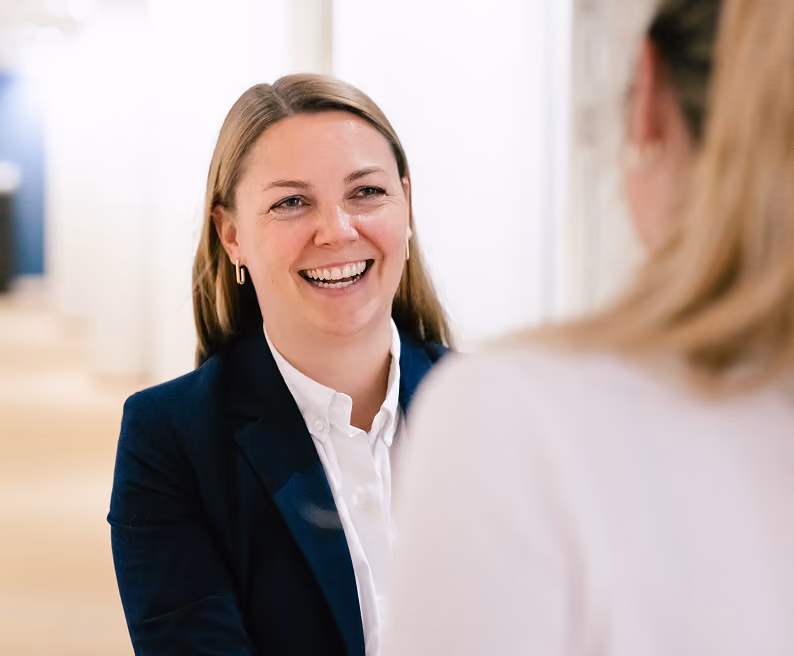Frau im Bewerbungsgespräch lächelt einer Gesprächspartnerin gegenüber.