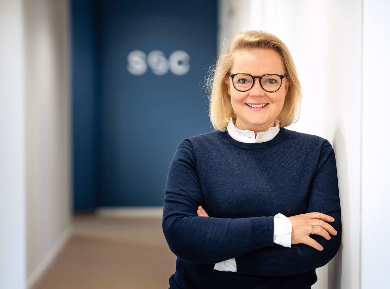 Porträt einer Frau mit Brille vor dem Struss-&-Claussen-Schriftzug.