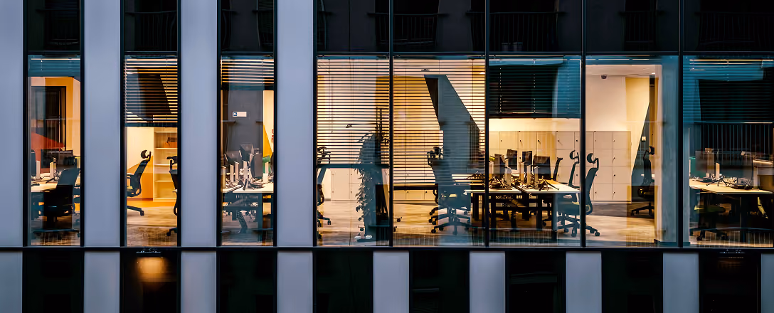 Bürogebäude mit beleuchteten Fenstern am Abend.