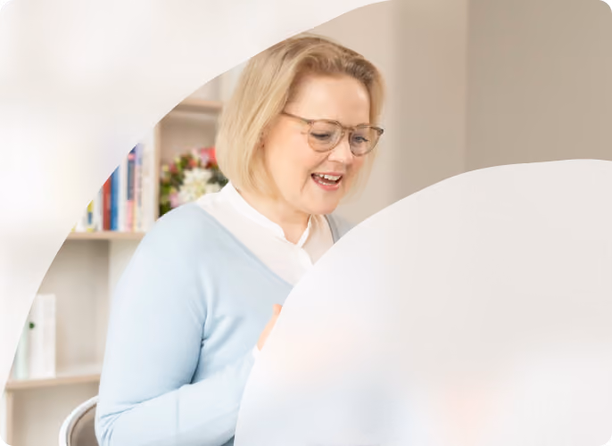 Frau mit Brille arbeitet in einem hellen Raum am Laptop.