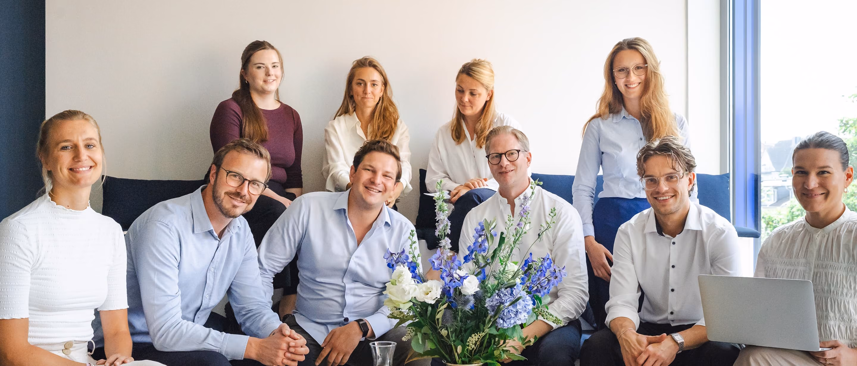 Das Struss-&-Claussen-Team sitzt gemeinsam in einem hellen Raum.