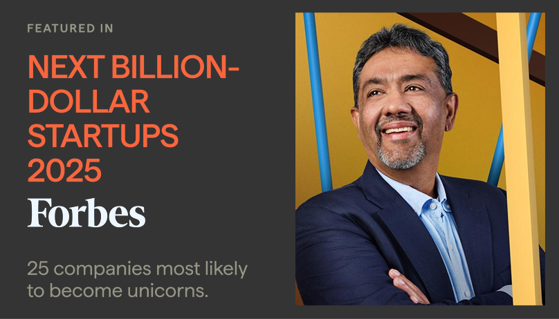 Portrait of a smiling man with short dark hair and beard wearing a blue suit and light blue shirt, standing with arms crossed against a yellow and blue geometric background, alongside text stating featured in Forbes Next Billion-Dollar Startups 2025 with 25 companies most likely to become unicorns.