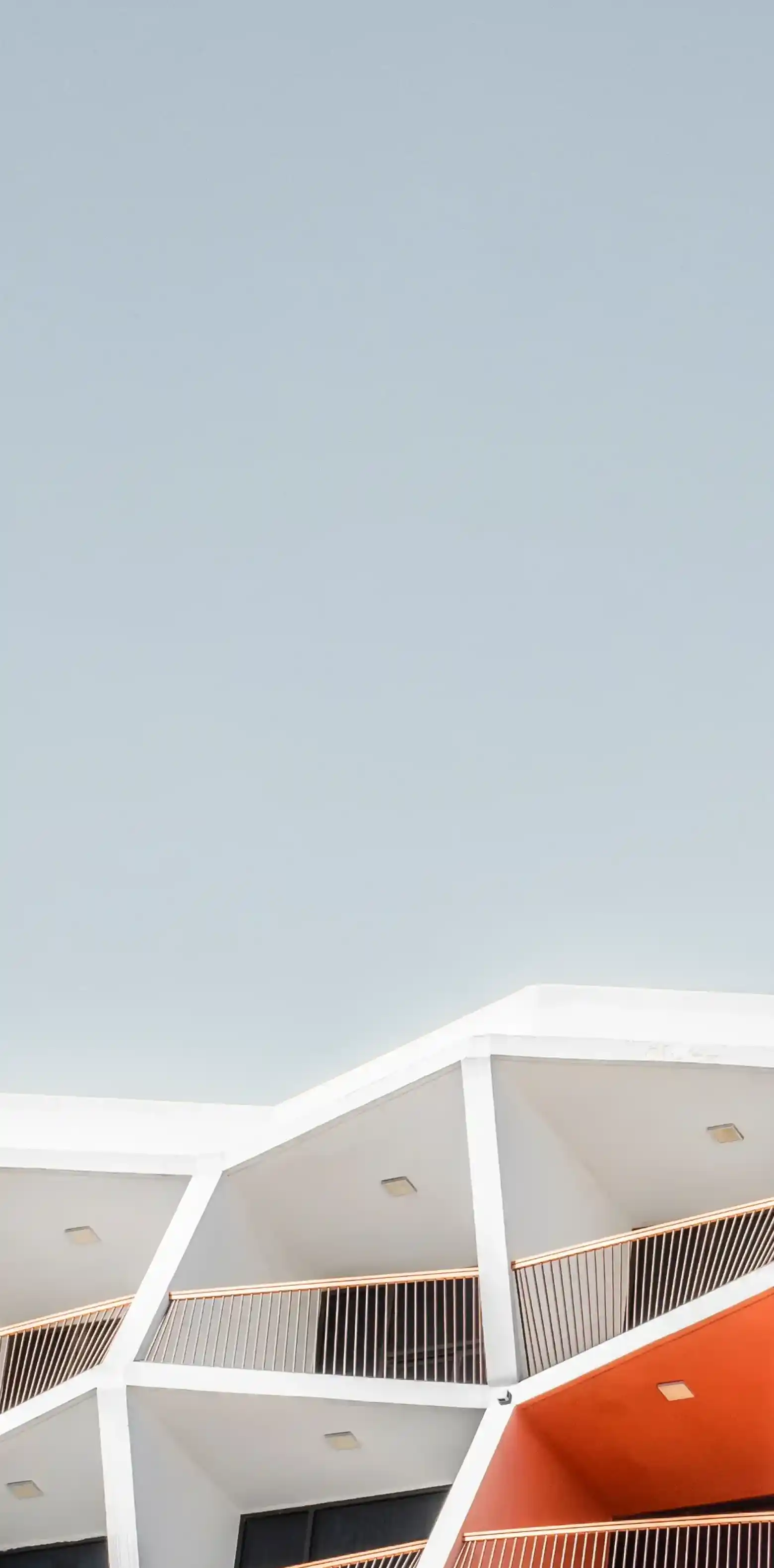 Close-up of a building roofline featuring a series of angular, folded concrete panels casting shadows.