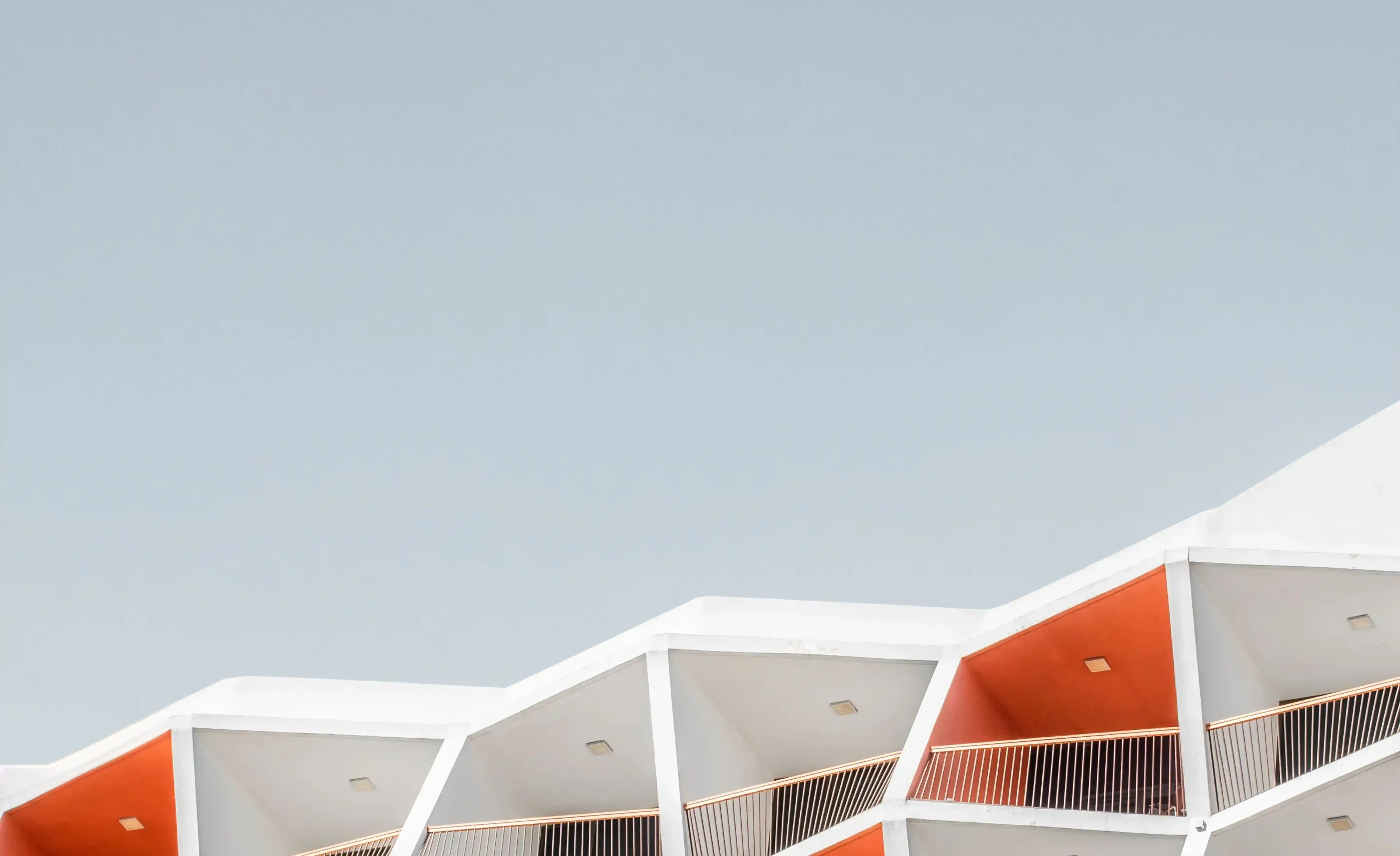 Close-up of a building roofline featuring a series of angular, folded concrete panels casting shadows.