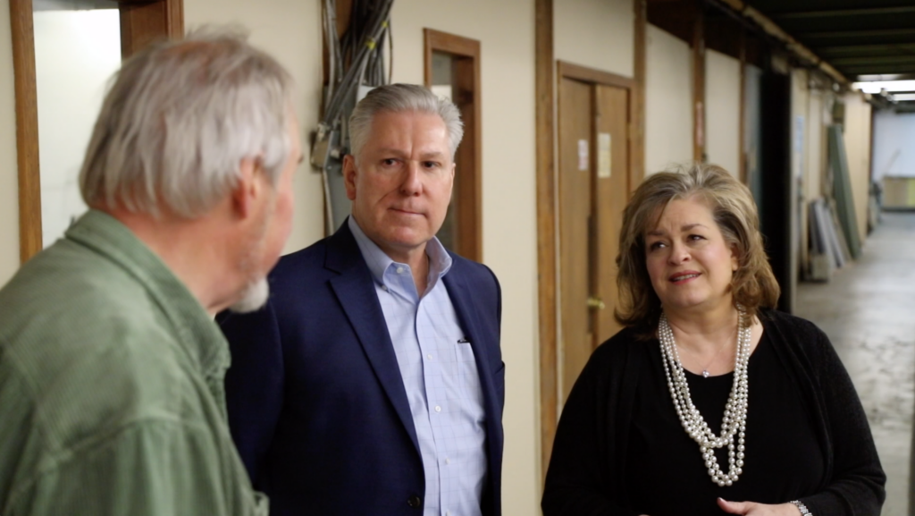 Three people in conversation in a corridor at a manufacturing facility.