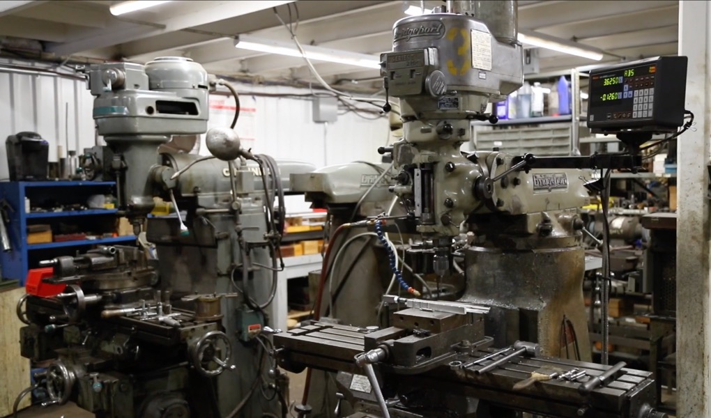 Bridgeport-style vertical milling machines with digital readouts in a working machine shop.