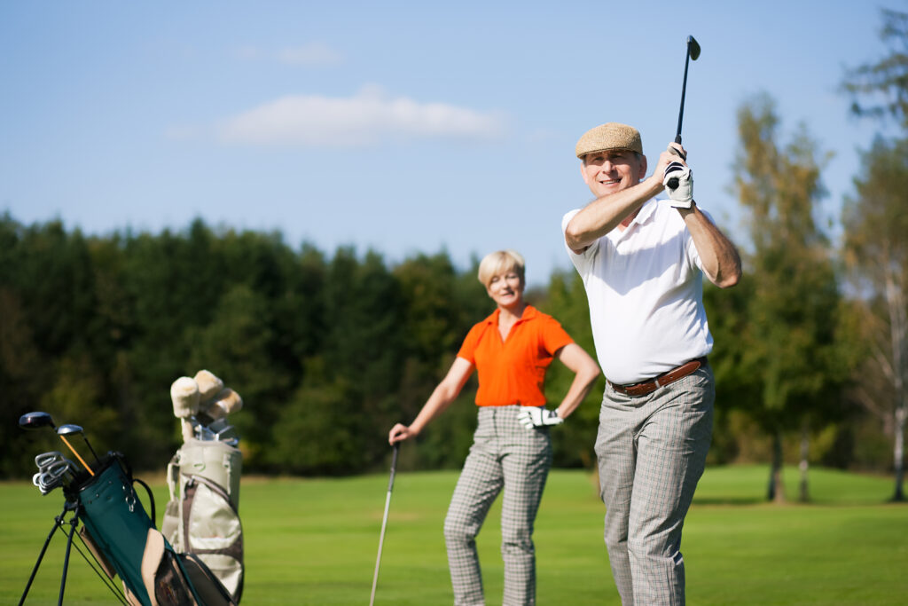 Out on the golf course are a husband an wife playing golf together.