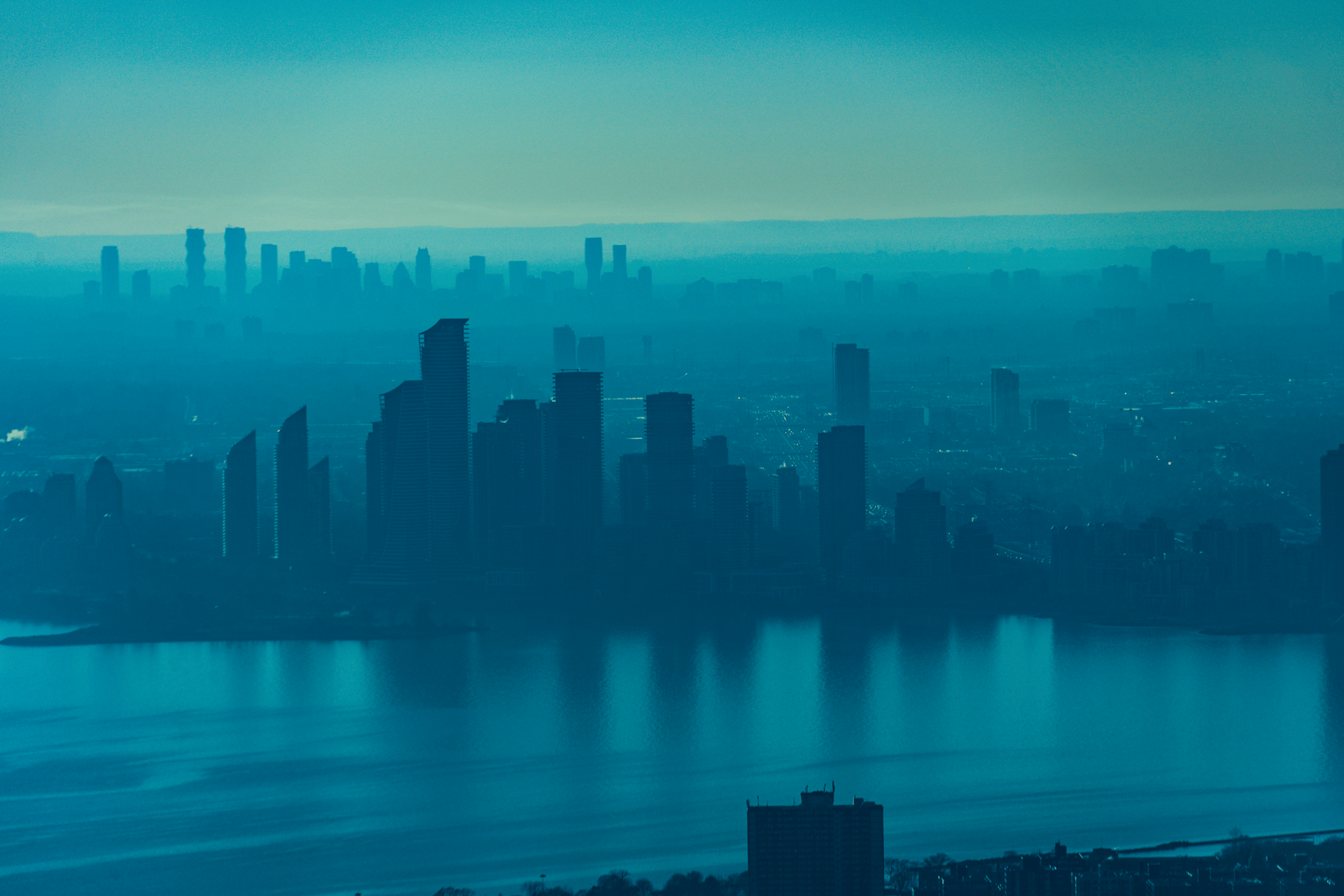 City skyline across the water under a hazy blue evening sky