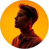 Portrait of a person in profile with short hair against a vibrant orange background.