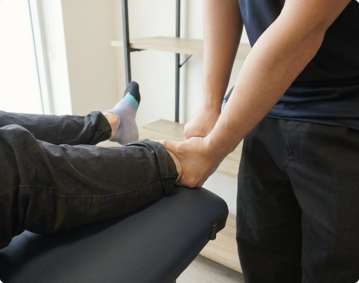 A physiotherapist assessing a patient's lower leg on a treatment table