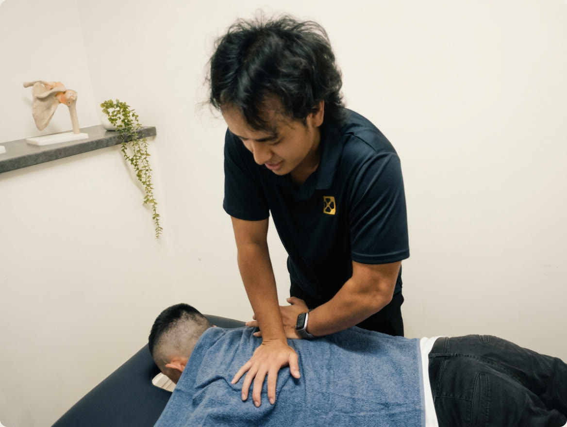 A Myogenesis practitioner treating a patient's lower back on a treatment table